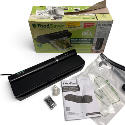 WT Outlets Foodsaver 2-in-1 vacuum sealing system in black with included bags, manual, and original packaging.