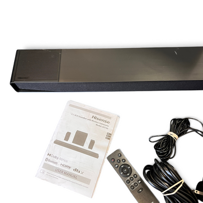 WT Outlets Hisense AX700 5.1.4 channel soundbar system with remote, manual, and cables on a grey carpet background.