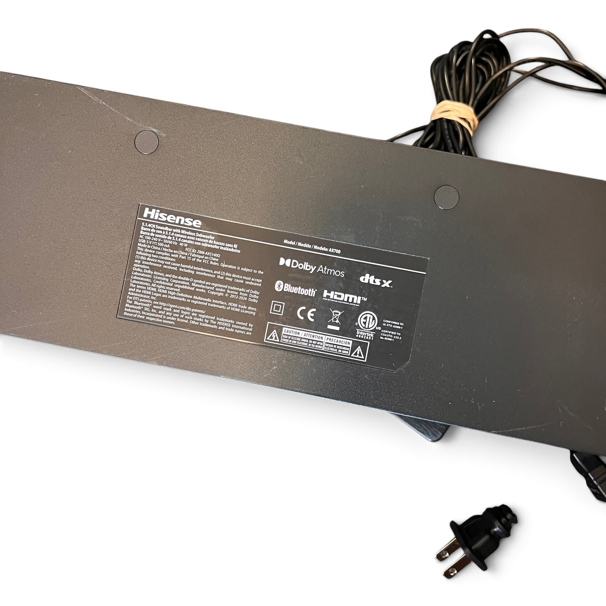 WT Outlets Hisense AX700 soundbar rear label with Dolby Atmos and DTS X branding, power cable, and user manual.